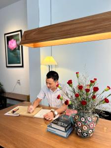 a man signing a document at a wooden table at Charming Riverside Hotel in Hue