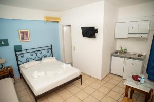 a bedroom with a white bed and a kitchen at Manos Rooms in Megas Yialos-Nites