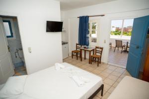 a room with two beds and a table and chairs at Manos Rooms in Megas Yialos-Nites