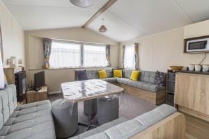 a living room with a couch and a table at Lovely Caravan With Decking At Seawick Holiday Park In Essex Ref 27471sw in Clacton-on-Sea