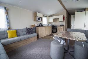 un soggiorno con divano e tavolo di Lovely Caravan With Decking At Seawick Holiday Park In Essex Ref 27471sw a Clacton-on-Sea