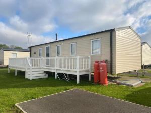 a house with a red fire hydrant in front of it at Lovely Caravan With Decking At Seawick Holiday Park In Essex Ref 27471sw in Clacton-on-Sea