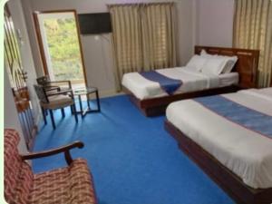 Almas Hotel Sylhet في Debpur: غرفة فندقية بسريرين وكرسي
