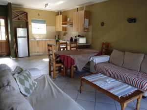 ein Wohnzimmer mit einem Sofa und einem Tisch sowie eine Küche in der Unterkunft Carmel Huys in Kapstadt