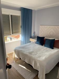 sypialnia z łóżkiem z niebieskimi poduszkami i oknem w obiekcie CASA BLANCA w mieście Torrevieja