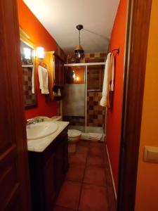 baño con paredes de color naranja, lavabo y aseo en La Casa de los Gatos, en Condemios de Abajo