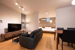 a living room with a couch and a bed and a television at Hotel AZUMA SEE in Tokyo