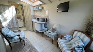 a living room with two chairs and a tv at Conygre Bungalow in Timsbury