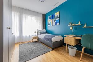 um quarto com uma cama, uma secretária e uma parede azul em Ambrosia Guesthouse em Rheinfelden