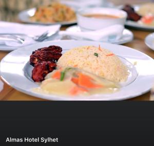 Almas Hotel Sylhet في Debpur: طبق من الطعام مع الرز واللحوم على الطاولة