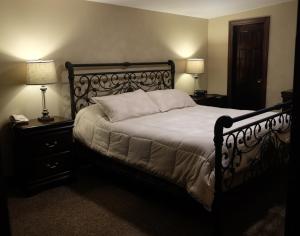 a bed in a bedroom with two lamps and two tables at Chalet Inn & Suites in Centerport