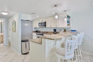a kitchen with white cabinets and white bar stools at Summer Haven D in Destin