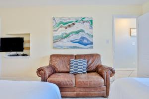 a brown leather chair in a bedroom with a painting at Summer Haven D in Destin