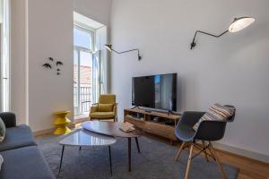 un soggiorno con TV, divano e sedie di Glamorous 3BDR Apartment in City Center by LovelyStay a Lisbona