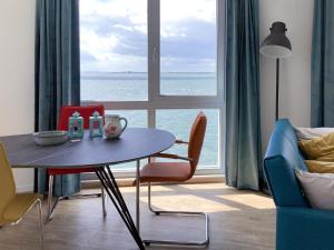 sala de estar con mesa, sillas y ventana grande en Sea view apartment in Scherpenisse with terrace, en Scherpenisse