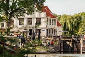 un bâtiment avec des personnes assises à l'extérieur, à côté d'une rivière dans l'établissement The Quay Amsterdam - FREE PARKING, à Amsterdam