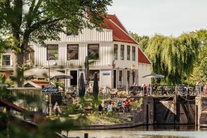 a building with people sitting outside next to a river at The Quay Amsterdam - FREE PARKING in Amsterdam