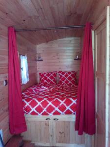 Schlafzimmer mit einem roten Bett mit roten Vorhängen in der Unterkunft Les Insolites de Nini in Grainville-Ymauville