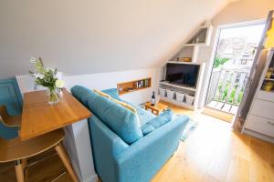 uma sala de estar com um sofá azul e uma mesa em The Loft at The Little Elms em Motcombe