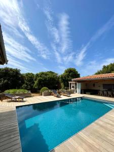 a swimming pool with a wooden deck and a house at Villa Alivu belle piscine chauffée in Bonifacio