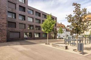 un edificio de ladrillo con un parque infantil delante de él en Ambrosia Guesthouse, en Rheinfelden