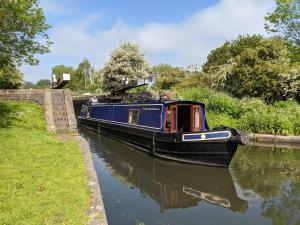 a blue boat is traveling down a canal at Narrow Escape - 50ft Boat on the Grand Union Canal, near Tring in Tring