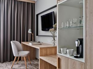 a room with a desk with a chair and a television at Hotel Great Polonia Kraków Airport - Ex Hotel Witek in Modlniczka