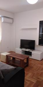 a living room with a flat screen tv and a coffee table at Lovely condo next to salt room, bus station in Skopje