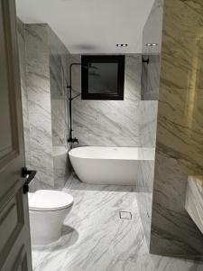 a bathroom with a bath tub and a toilet at The Key - Luxury Apartment in Doha