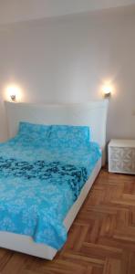 a bedroom with a bed with blue sheets and a wooden floor at Lovely condo next to salt room, bus station in Skopje