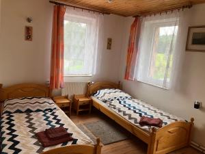 a bedroom with two beds and two windows at Penzion Restaurace Zátiší in Rumburk