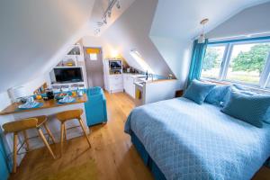 a bedroom with a blue bed and a kitchen at The Loft at The Little Elms in Motcombe
