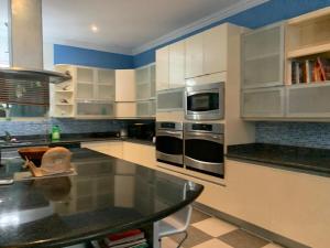 Room in House - Casa De Playa Alegria, Flamingo, في بلايا فلامنغو: مطبخ فيه دواليب بيضاء وطاولة فيه