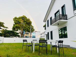 een tafel en stoelen in het gras voor een gebouw bij Kulai Lagenda Putra Corner House 古来公主城民宿 near JPO in Kulai