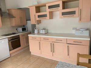 uma cozinha com armários de madeira e electrodomésticos brancos em Starlight Self Service Accommodation em Leigh