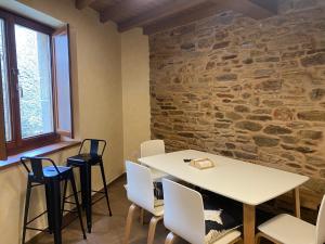 a room with a table and chairs and a stone wall at Casa da Cota in Monterroso