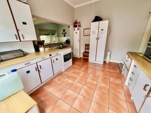 cocina con armarios blancos y suelo de baldosa en 23 Ambleside Holiday Retreat by the sea, en Port Shepstone
