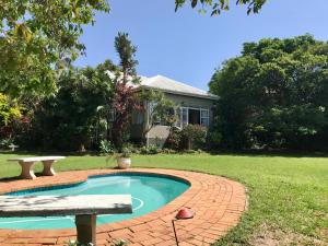 a swimming pool with a bench and a house at 23 Ambleside Holiday Retreat by the sea in Port Shepstone