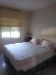 una camera da letto con un letto con lenzuola bianche e una finestra di Berna a Jerez de la Frontera