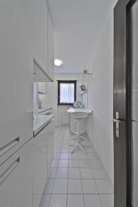 a white kitchen with a sink and a table at Chesa Arlas - St. Moritz in St. Moritz