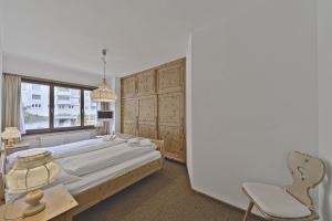 Chesa Arlas - St. Moritz في سان موريتز: غرفة نوم بسرير وكرسي ونافذة