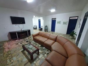 ein Wohnzimmer mit einem braunen Ledersofa und einem TV in der Unterkunft Linda casa com banho natural em Guaramiranga in Guaramiranga