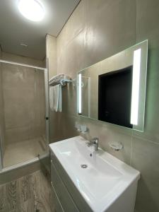 uma casa de banho com um lavatório, um chuveiro e um espelho. em Hotel Atmosphere em Poltava