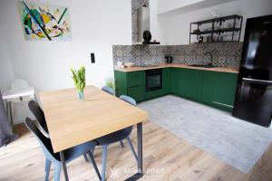 a kitchen with green cabinets and a wooden table at Sun&Sport apartament GÓRSKA OSTOJA +prywatna sauna in Szczyrk