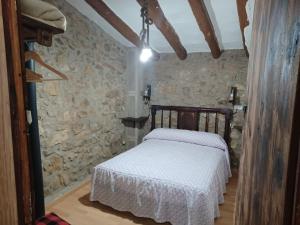1 dormitorio con 1 cama en una pared de piedra en Casa Leonor, en Bel