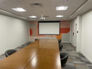 una sala de conferencias con una mesa grande y una pantalla blanca en The Orbit Hotel, Trademark Collection by Wyndham, en Fairview Park