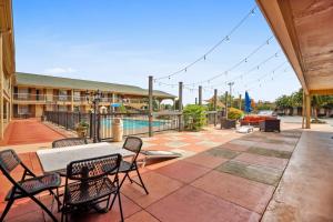 un patio con mesa, sillas y piscina en The Guest Lodge Gainesville, en Gainesville