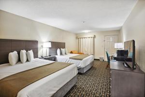 a hotel room with two beds and a flat screen tv at The Guest Lodge Gainesville in Gainesville