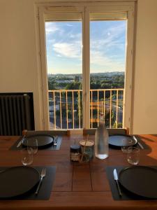 a dining table with a view of a large window at LE PERSICOPE Appart complet, 2 chambres à 5 min du centre ville in Mondeville