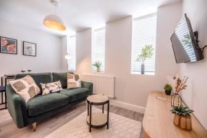 a living room with a green couch and a table at Guildhall Street Apartment in Bury Saint Edmunds